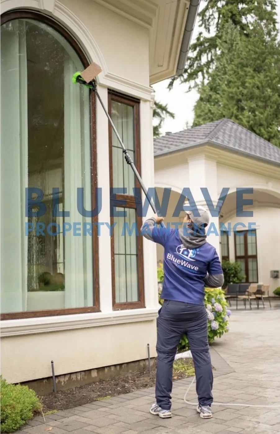BlueWave technician working near a home's exterior windows with landscaping protected by a tarp